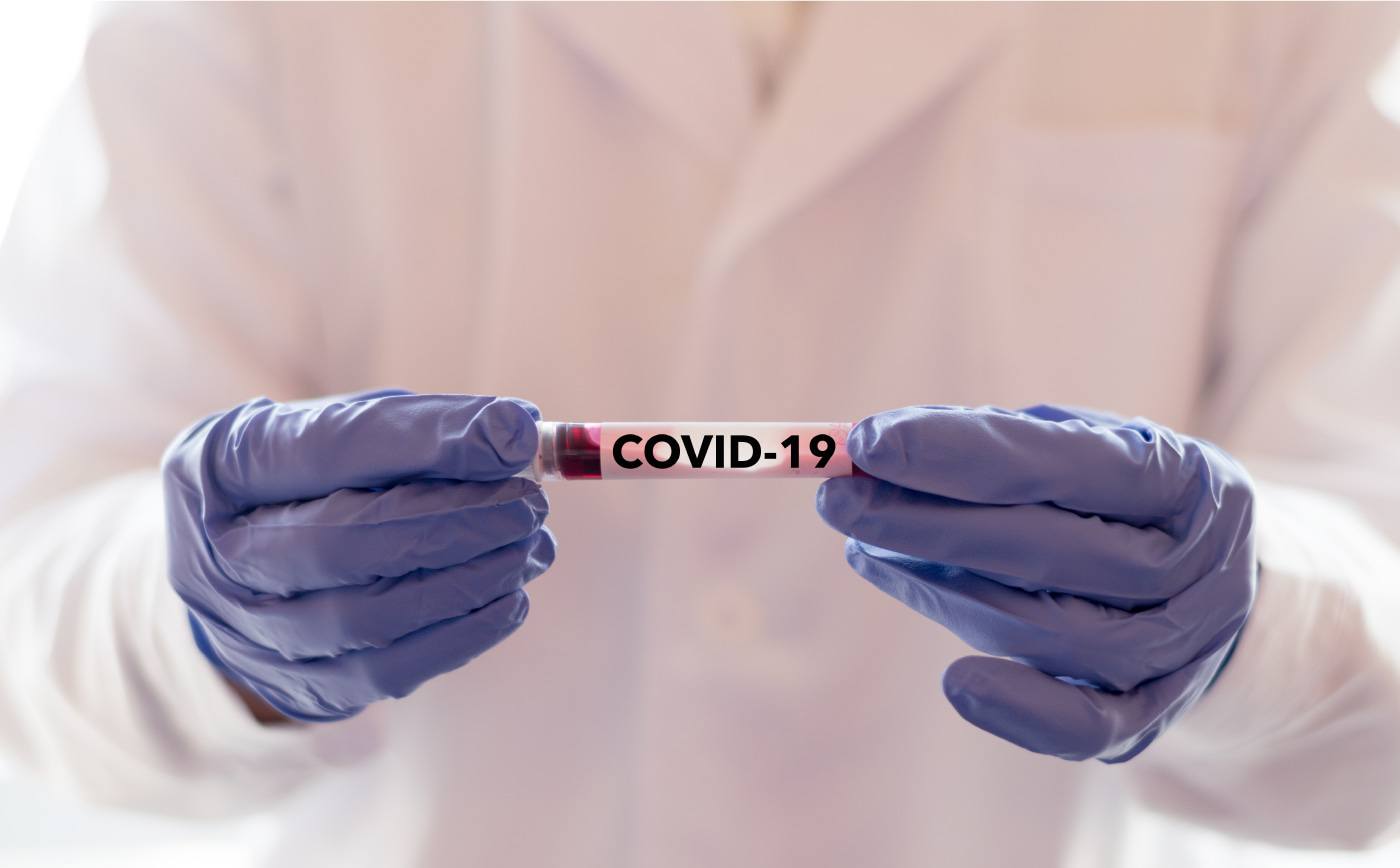 medical professional holding test tube labeled COVID-19